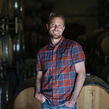 Man standing in front of wine barrels