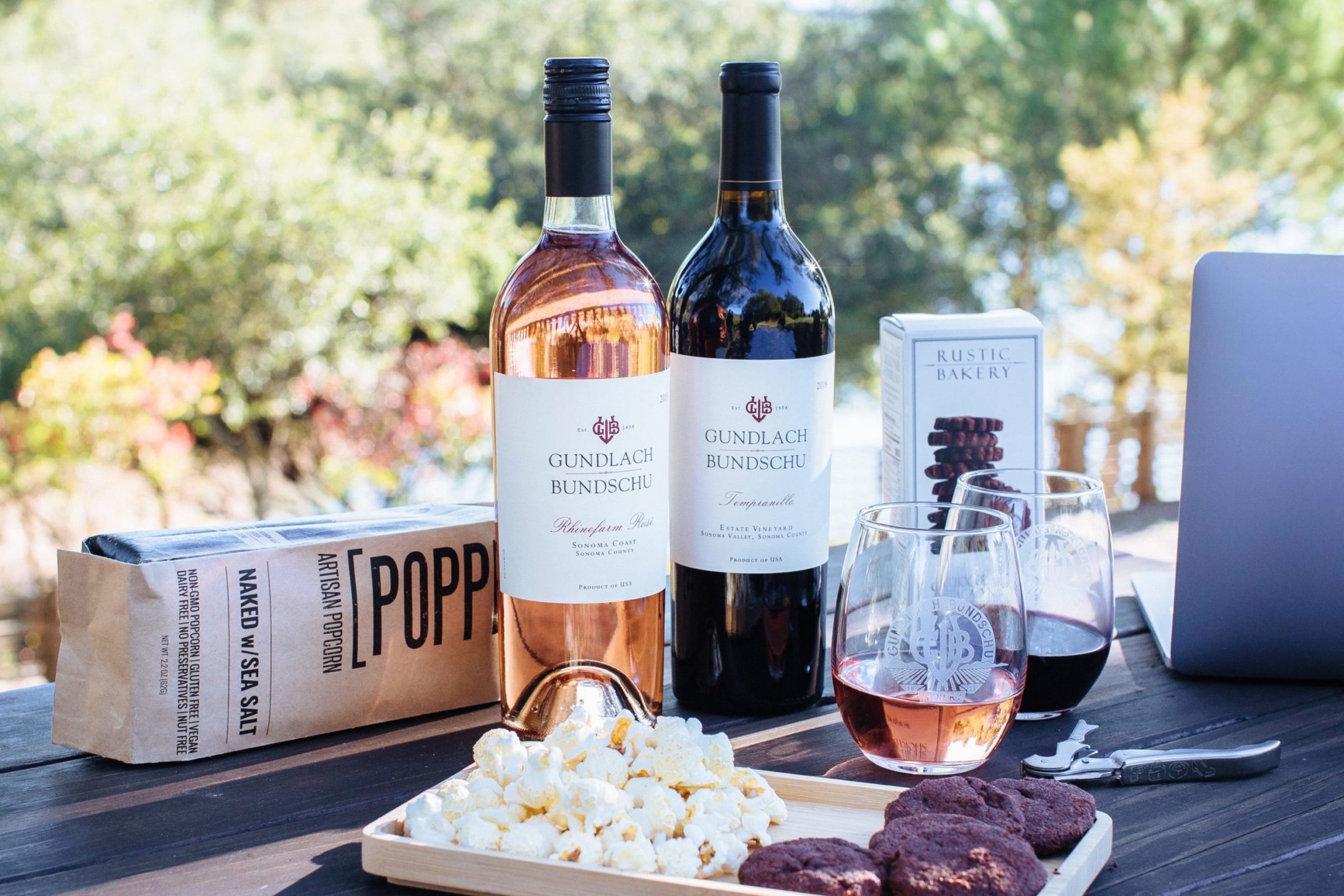 Bottles of wine, popcorn, cookies and laptop