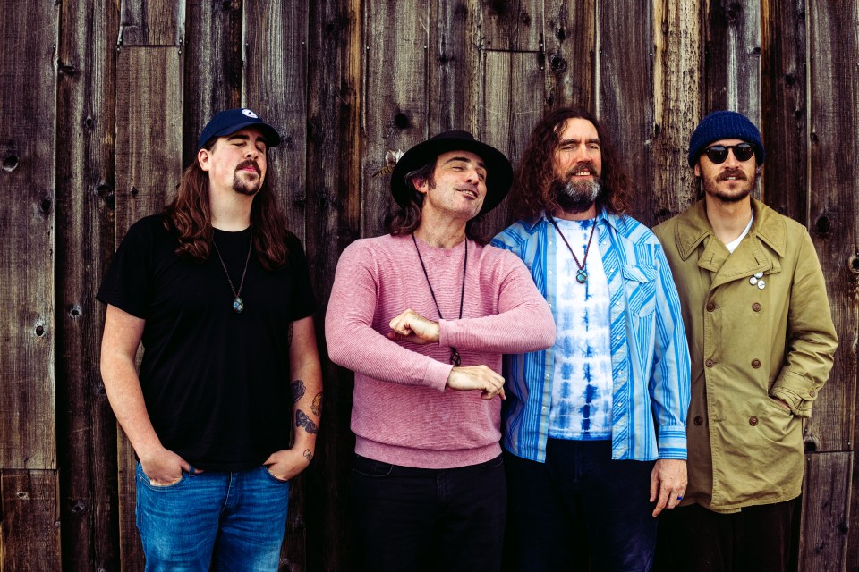 Four men in front of a wooden wall