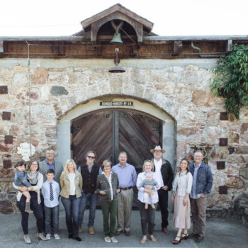 People standing in front of a stone building with large arched wooden doors