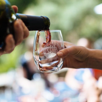 Close-up of red wine being poured into a stemless wine glass