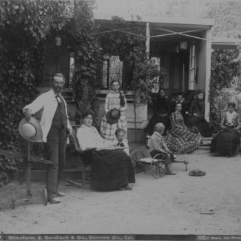 Black and white image of people standing and sitting in front of a house