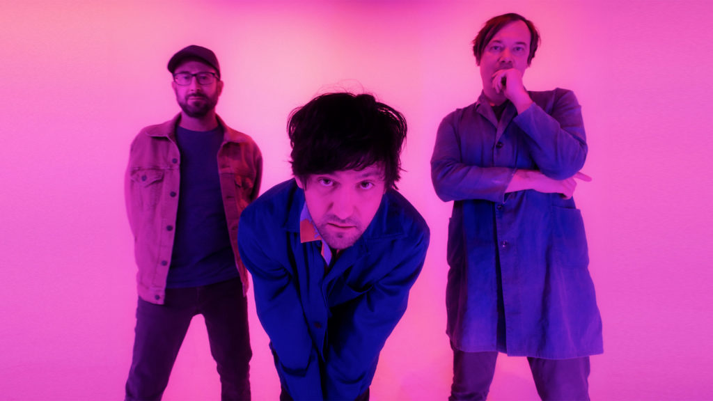 3 people, one bending over in a pink room