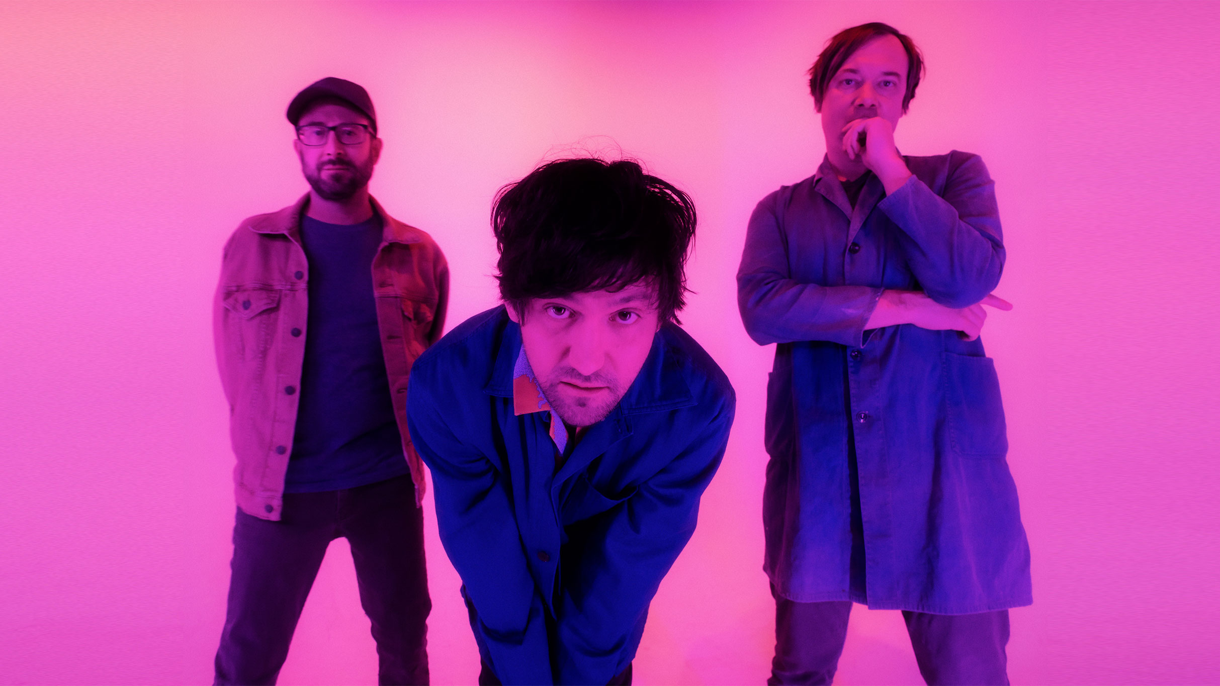 3 people, one bending over in a pink room