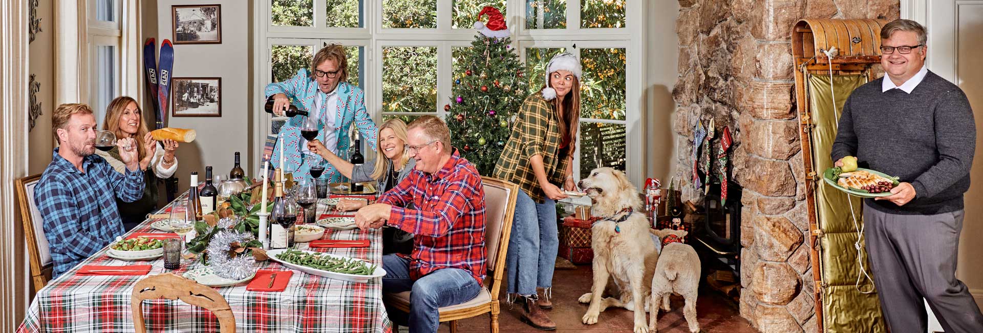 People gathered around a holiday table with food and wine